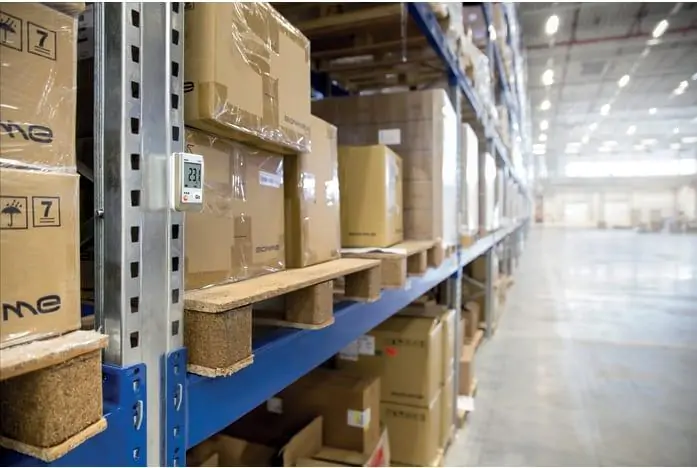 Temperature logger mounted on warehouse shelving beside boxed inventory